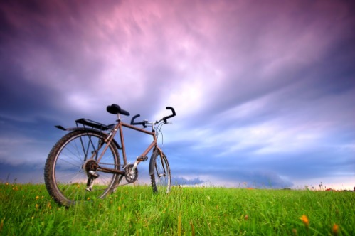 Dynamic photo of bike standing alone in grassland - with free space above.